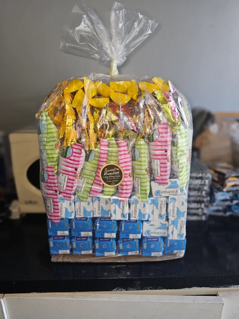 Tall Sweet Munchies snack hamper wrapped in cellophane, filled with candy and biscuit packs and topped with gold ribbon curls