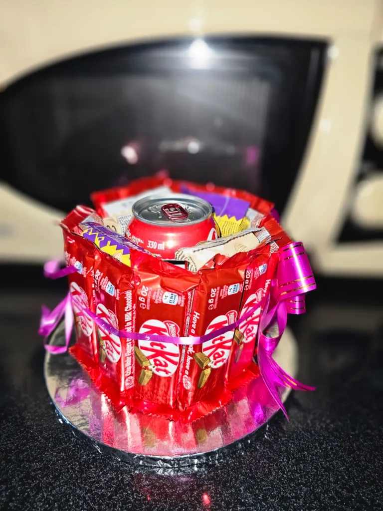 Chocolate bouquet made from KitKat bars wrapped in a ring around a soft drink can, tied with a pink ribbon