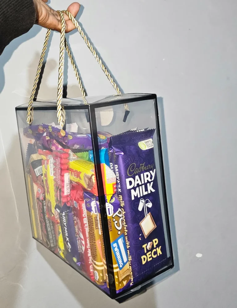 Clear gift bag with gold rope handles filled with assorted chocolate bars including Cadbury Dairy Milk